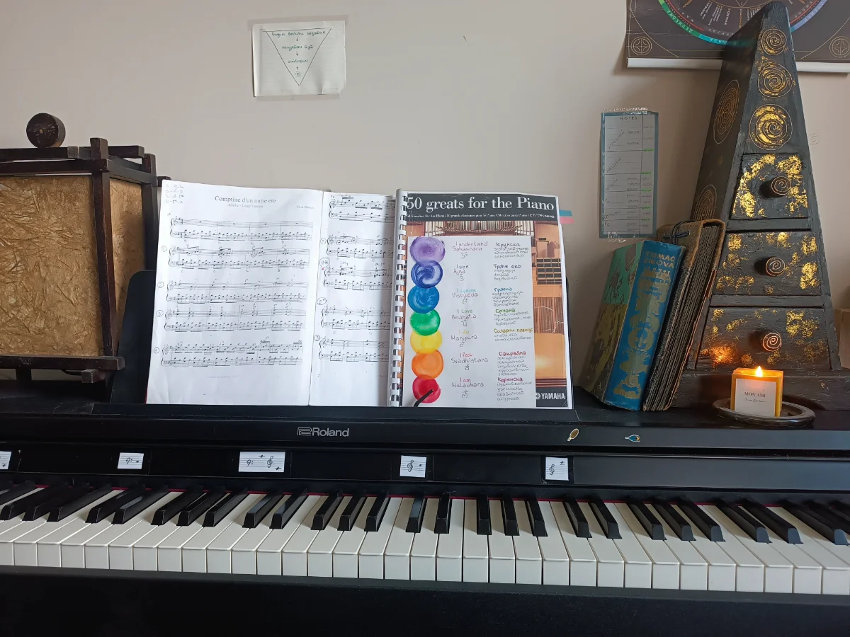 A piano with sheet music on the stand and a lit candle beside it